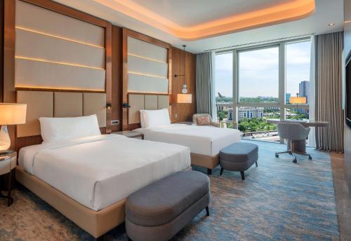 a hotel room with two beds and a desk at Hilton Tashkent City in Tashkent
