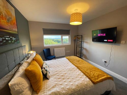 a bedroom with a large bed with a television on the wall at Luxury 1 bed Flat + sofa bed- Dudley 