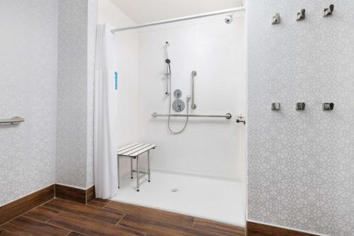 a shower stall with a stool in a bathroom at Hampton Inn Oakhurst-Yosemite in Oakhurst