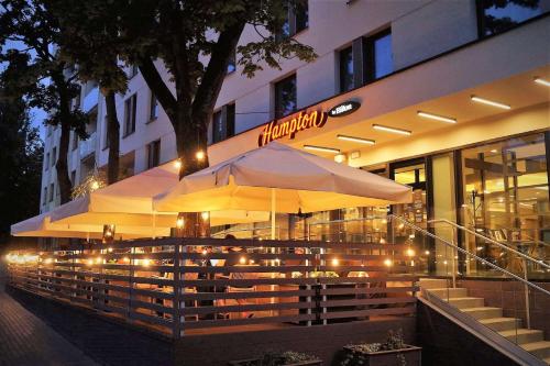 Hampton By Hilton Bialystok في بياويستوك: مطعم فيه مظله امام مبنى