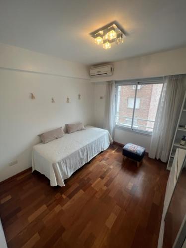 a bedroom with a white bed and a wooden floor at MANU. Moderno 2 dormitorios grande y luminoso. 2 baños. Cochera. Amenities in Rosario
