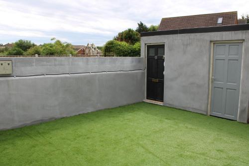 a backyard with a concrete wall and a yard with green grass at Penn Gardens Flat 1 - 2 - 3 & 4 Apartments in Havering atte Bower