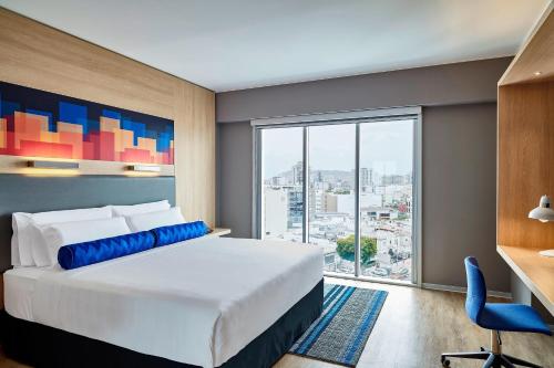 a bedroom with a bed and a desk and a large window at Aloft Lima Miraflores in Lima