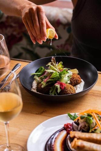 a person holding a slice of lemon next to a bowl of food at Southern Cross Hotel in Sydney