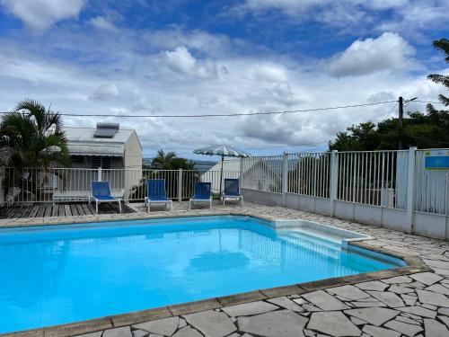 einen Pool mit einem Zaun und blauen Stühlen in der Unterkunft Studio de l'Anse Mitan in Les Trois-Îlets