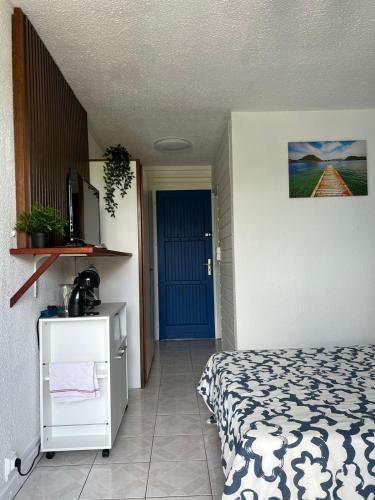 - une chambre avec un lit et une porte bleue dans l'établissement Studio de l'Anse Mitan, à Les Trois-Îlets