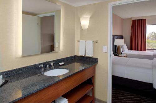 uma casa de banho do hotel com um lavatório e uma cama em Embassy Suites by Hilton Phoenix Scottsdale em Phoenix