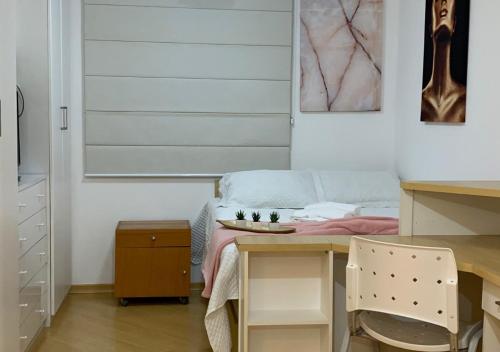a room with a desk and a bed with a table at Studio completo com vaga entre o Centro e Cambuí in Campinas