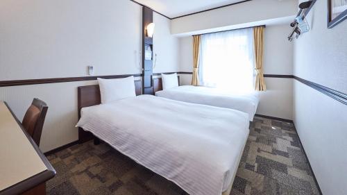 - 2 lits dans une petite chambre avec fenêtre dans l'établissement Toyoko Inn Osaka Tsutenkaku Mae, à Osaka