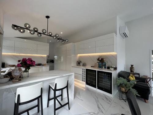 a kitchen with white cabinets and a bar with chairs at Okahu Bay Villas in Auckland