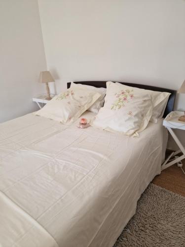 un grand lit blanc avec des draps et des oreillers blancs dans l'établissement Camélia rouge, à Granville