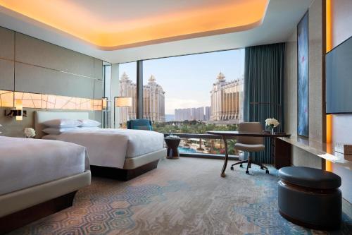 a hotel room with a bed and a desk with a view at JW Marriott Hotel Macau in Macau