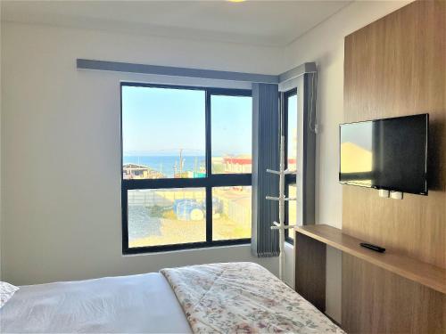 a bedroom with a bed and a large window at 150m da praia em um fantástico edifício em Balneário Piçarras in Piçarras