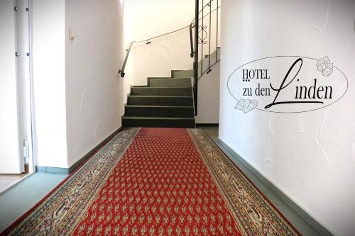 a hallway with a red rug on the floor and stairs at Hotel zu den Linden in Wachtberg