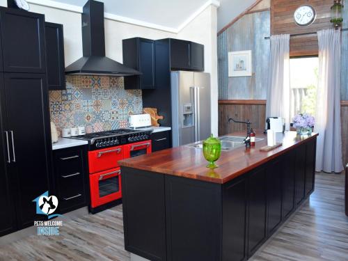 a kitchen with black cabinets and a red stove top oven at A Beautiful Property, Walking Distance to the Beach in Esperance WA! in Esperance