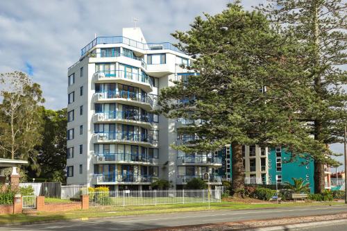 a tall white building with a tree in front of it at Heritage 303 in Tuncurry