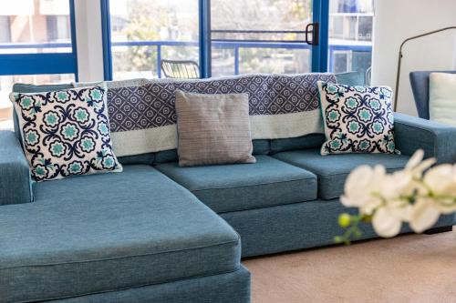 a blue couch with pillows in a living room at Heritage 303 in Tuncurry