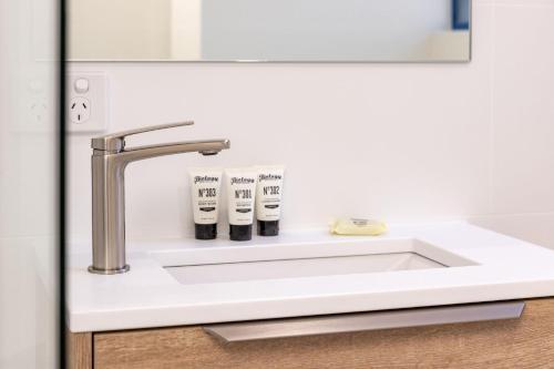 a bathroom sink with two toothbrushes at Heritage 303 in Tuncurry