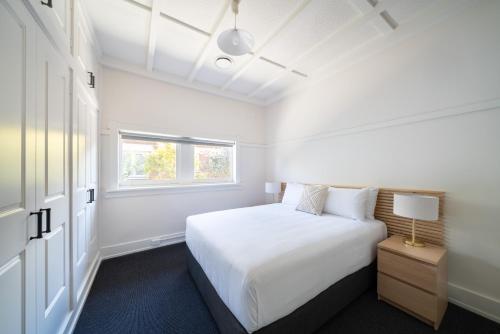 a white bedroom with a bed and a window at Heritage Inn Bathurst in Bathurst