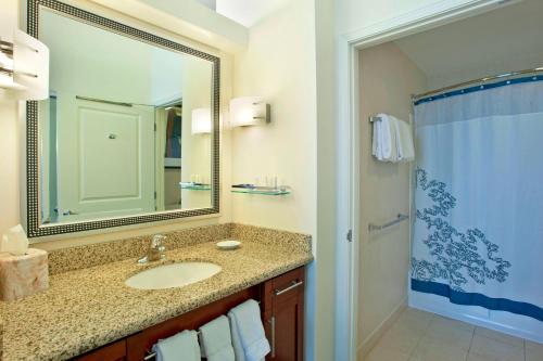 ein Bad mit einem Waschbecken, einem Spiegel und einer Dusche in der Unterkunft Residence Inn Baltimore Hunt Valley in Hunt Valley