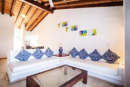 a living room with a white couch and blue pillows at Hotel Suites Mar Elena in Puerto Vallarta