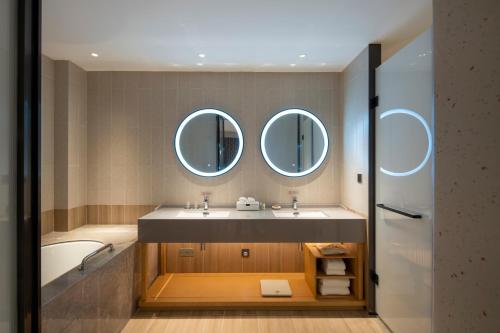 uma casa de banho com um lavatório e 2 espelhos em Hilton Garden Inn Changchun Economic Development Zone em Changchun