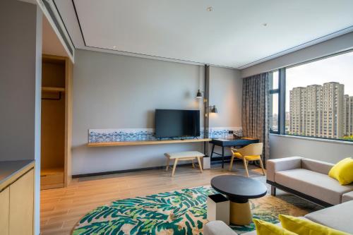 a living room with a couch and a table with a tv at Hilton Garden Inn Changchun Economic Development Zone in Changchun
