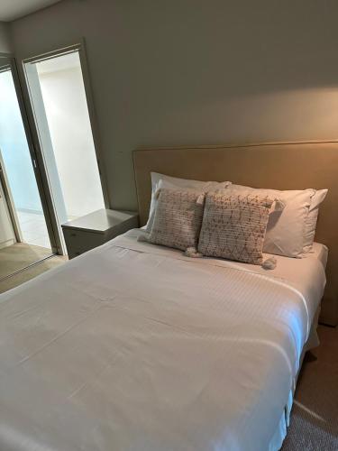 Cama con sábanas blancas y almohadas junto a una ventana en ANTEA apartments Embassy free parking en Adelaida
