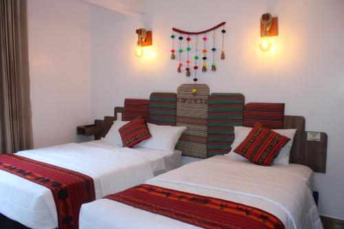 two beds in a room with white walls and lights at Collection Machupicchu in Machu Picchu