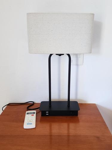 a lamp on a table with a phone and a remote control at Bella Villa Roomy apartment at 5 min walk to the beach in Las Galeras