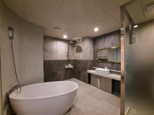 Rein Hotel Busan Yeonsan في بوسان: حمام مع حوض كبير ومغسلة