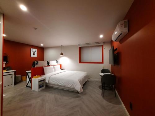 a bedroom with a white bed and a red wall at Rein Hotel Busan Yeonsan in Busan