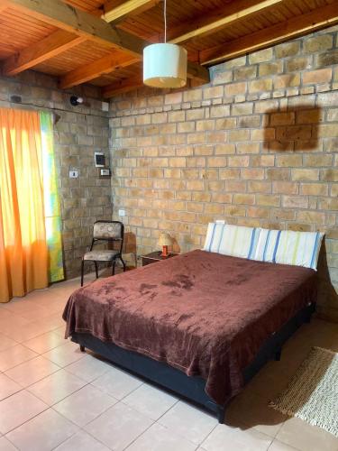 een slaapkamer met een bed en een bakstenen muur bij Casa 2 dormitorios in Oberá