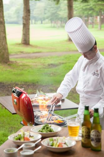 a man in a chefs hat preparing food on a table at The Prince Villa Karuizawa in Karuizawa