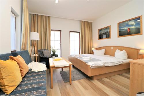 um quarto de hotel com uma cama e um sofá em Deutsches Haus Zimmer 19 em Wustrow