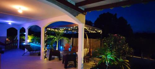 a house with a patio at night with lights at Kukumi's House avec Piscine in Sainte-Anne