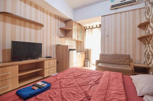 a bedroom with a bed and a flat screen tv at Apartment Green Lake View Ciputat by Celebrity Room in Pondokcabe Hilir