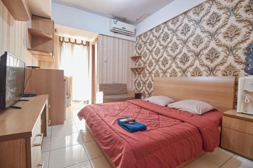 a bedroom with a bed with a red comforter at Apartment Green Lake View Ciputat by Celebrity Room in Pondokcabe Hilir