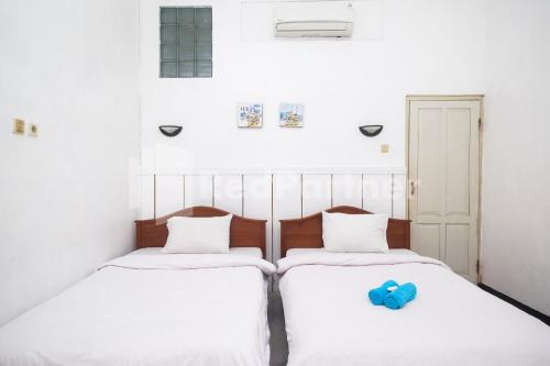 twee bedden met witte lakens en een blauw speeltje erop bij Hotel Limaran 1 Syariah Malioboro Mitra RedDoorz in Sentool