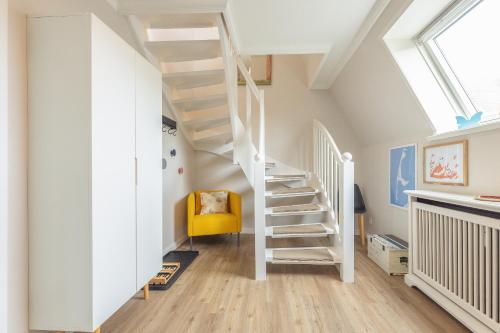escalera blanca en una habitación con silla amarilla en Appartement Sylter Glück, en Westerland