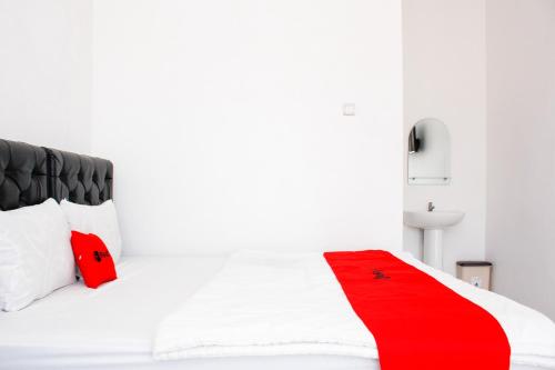 a white bed with red pillows and a red blanket at RedDoorz Syariah near Kawasan Wisata Gunung Prau Dieng in Dieng