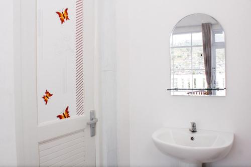 a white bathroom with a sink and a mirror at RedDoorz Syariah near Kawasan Wisata Gunung Prau Dieng in Dieng