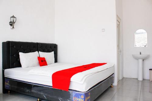a bedroom with a bed with a red blanket on it at RedDoorz Syariah near Kawasan Wisata Gunung Prau Dieng in Dieng