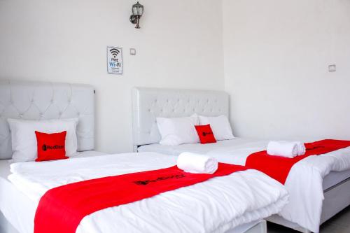 two beds in a room with red and white sheets at RedDoorz Syariah near Kawasan Wisata Gunung Prau Dieng in Dieng