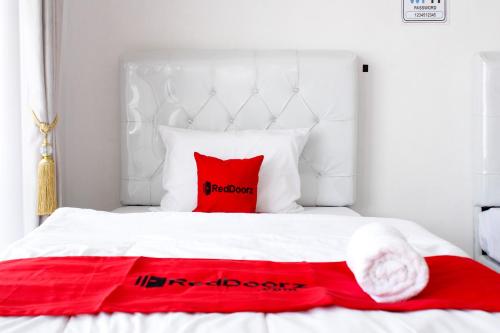 a white bed with red pillows on it at RedDoorz Syariah near Kawasan Wisata Gunung Prau Dieng in Dieng