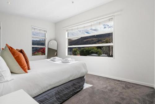 a white bedroom with a large bed and two windows at Whakata on McBride in Queenstown