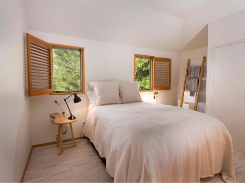 una camera con un letto bianco e due finestre di Kumiko's Guest House a Omihi