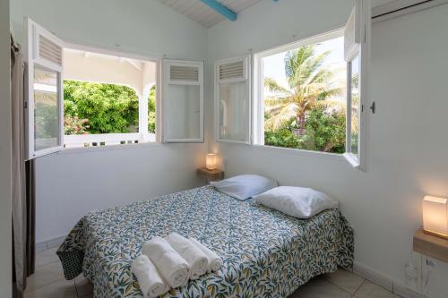 um quarto com uma cama com duas almofadas e duas janelas em Résidence Les Carlettes em Saint-François