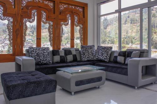 a living room with a couch and chairs and windows at RedDoorz Syariah near Kawasan Wisata Gunung Prau Dieng in Dieng