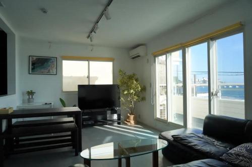 a living room with a couch and a tv at Zaimokuza SOLA 鎌倉材木座 in Kamakura